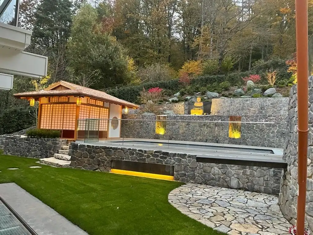 beleuchtetes japanisches Teehaus in Daemmerung und Schwimmbad